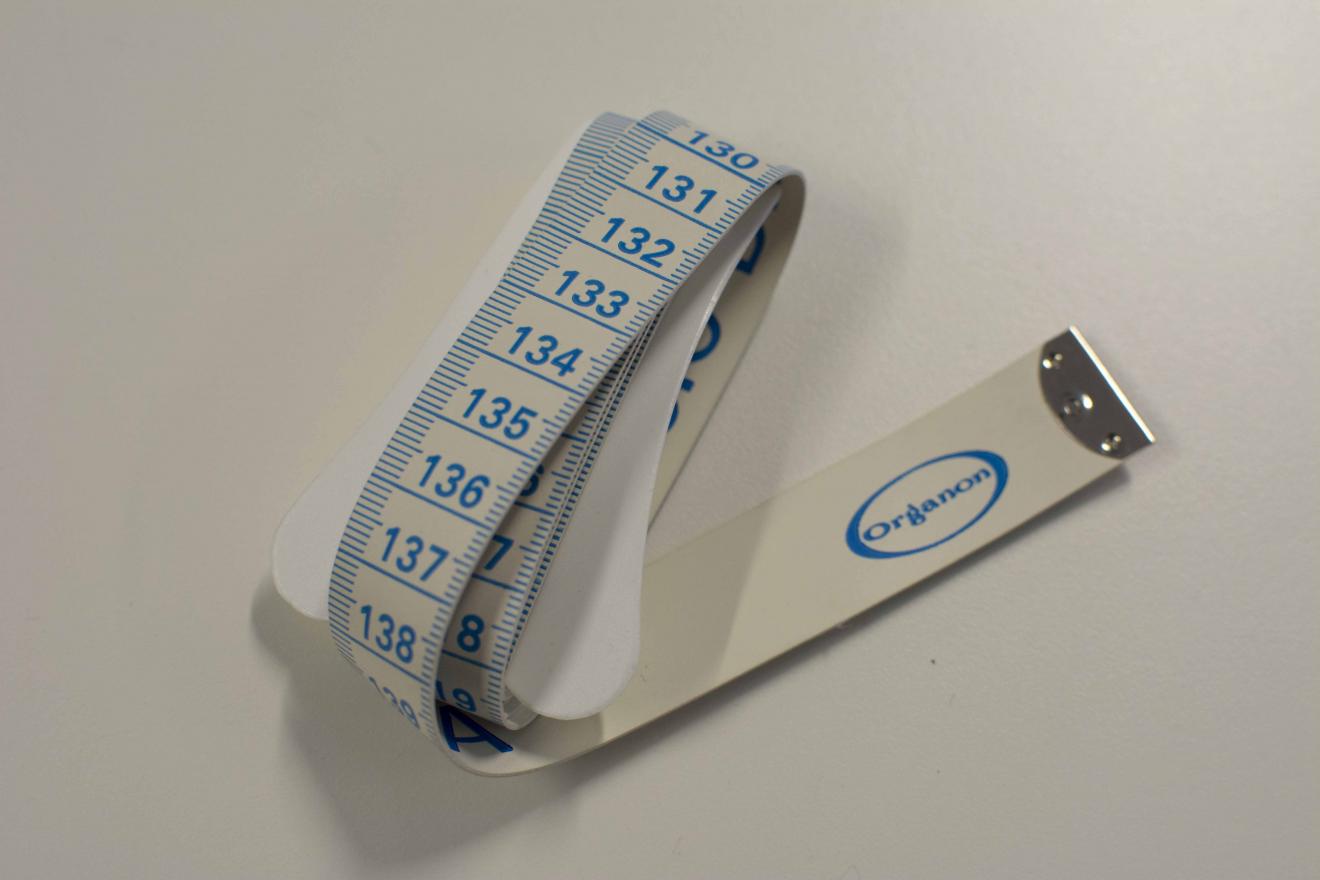 Cinta métrica blanca con numeración azul y remate metálico en uno de los extremos