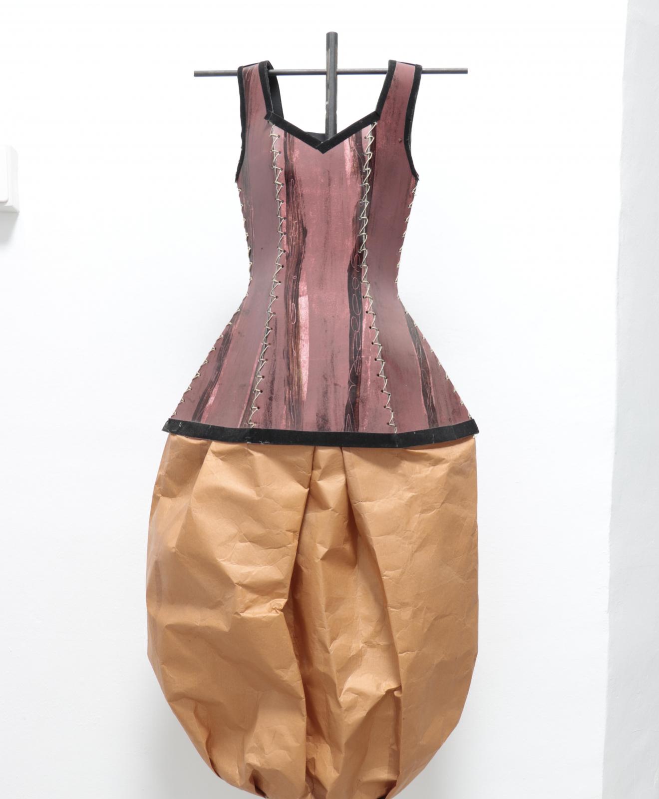 Vestido escultura compuesto por corpiño rosa envejecido de material rígido cosido en secciones verticales, bajo el que se abre una falda globo de papel marrón